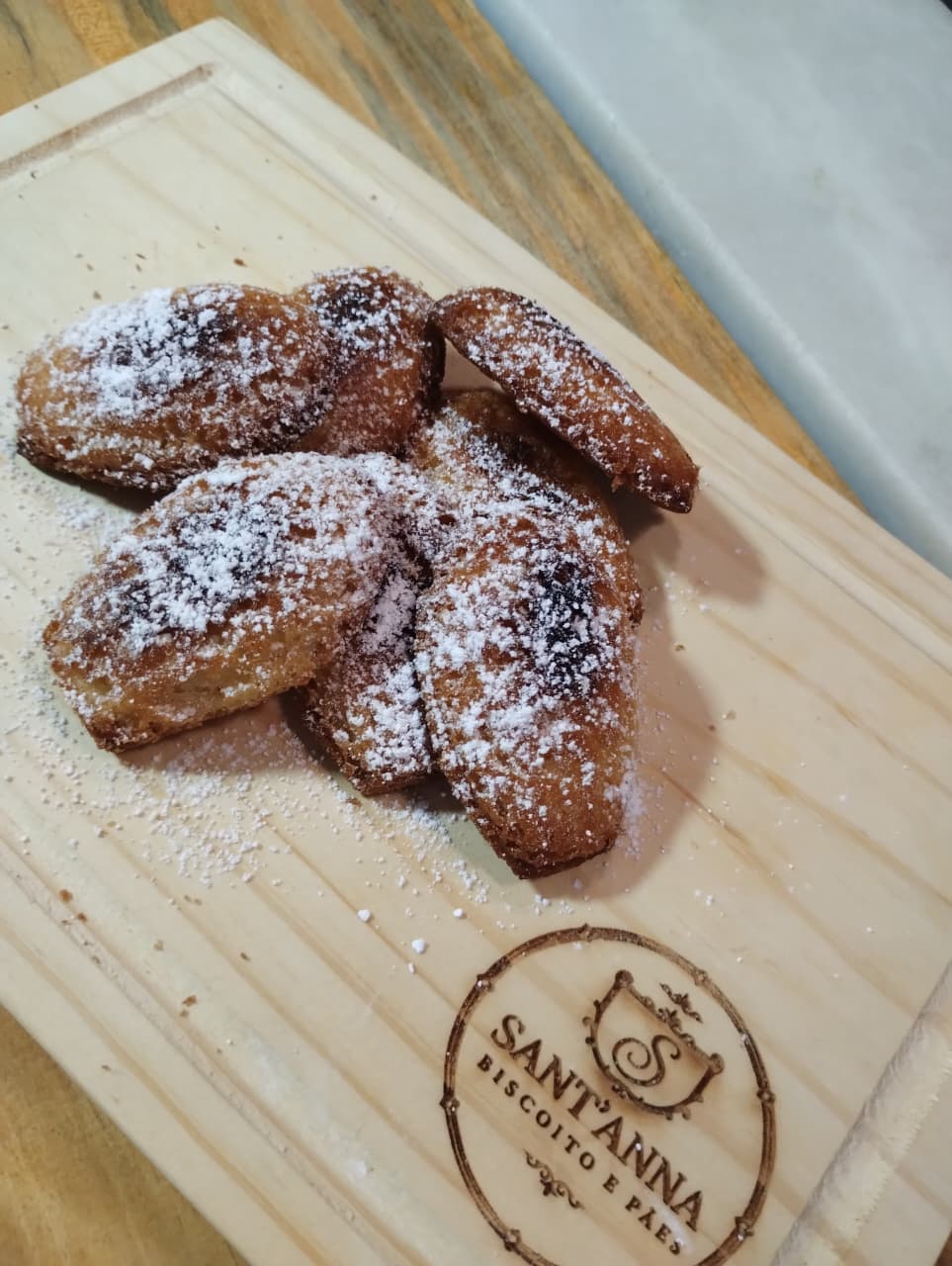 Madeleine: O bolinho francês em forma de concha: massa amanteigada, macia por dentro e douradinha na beirada, com açúcar de confeiteiro por cima. F...
